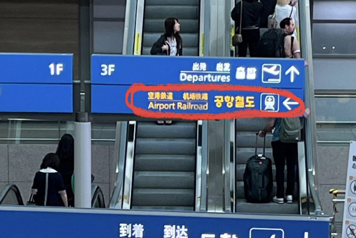 Blue overhead sign in Incheon Airport reading Airport Railroad with an arrow, circled in red