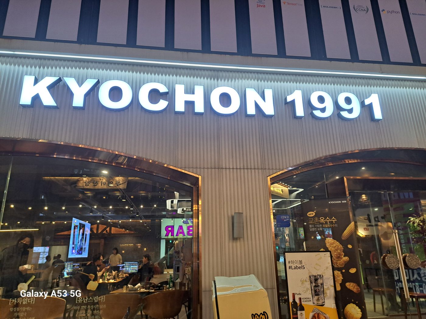 The lit KYOCHON 1991 storefront sign at night in Jongno, Seoul, with diners visible inside